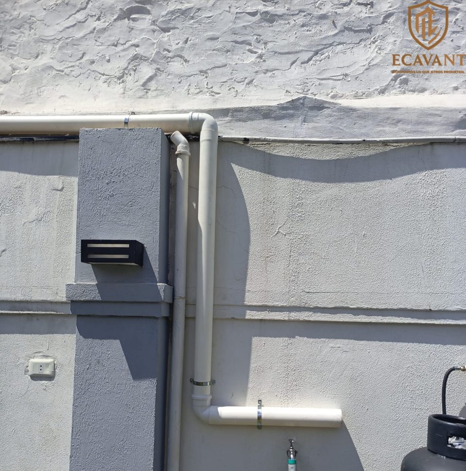 Bajada de caño de PVC para cableado fijada con abrazaderas en un muro exterior