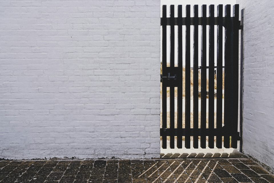 Portón negro de barrotes junto a una pared blanca