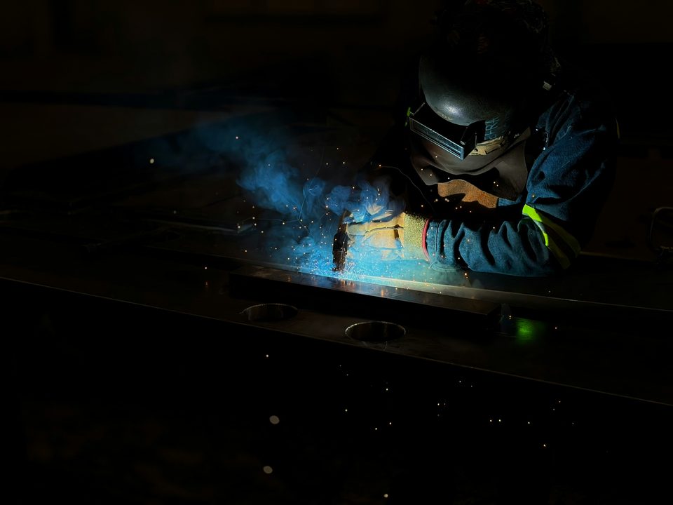 Soldador con careta trabajando una pieza de metal