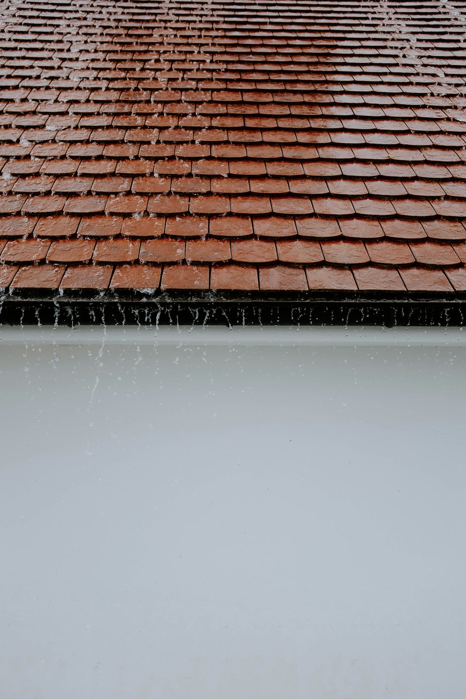 Agua de lluvia escurriendo por un techo de tejas